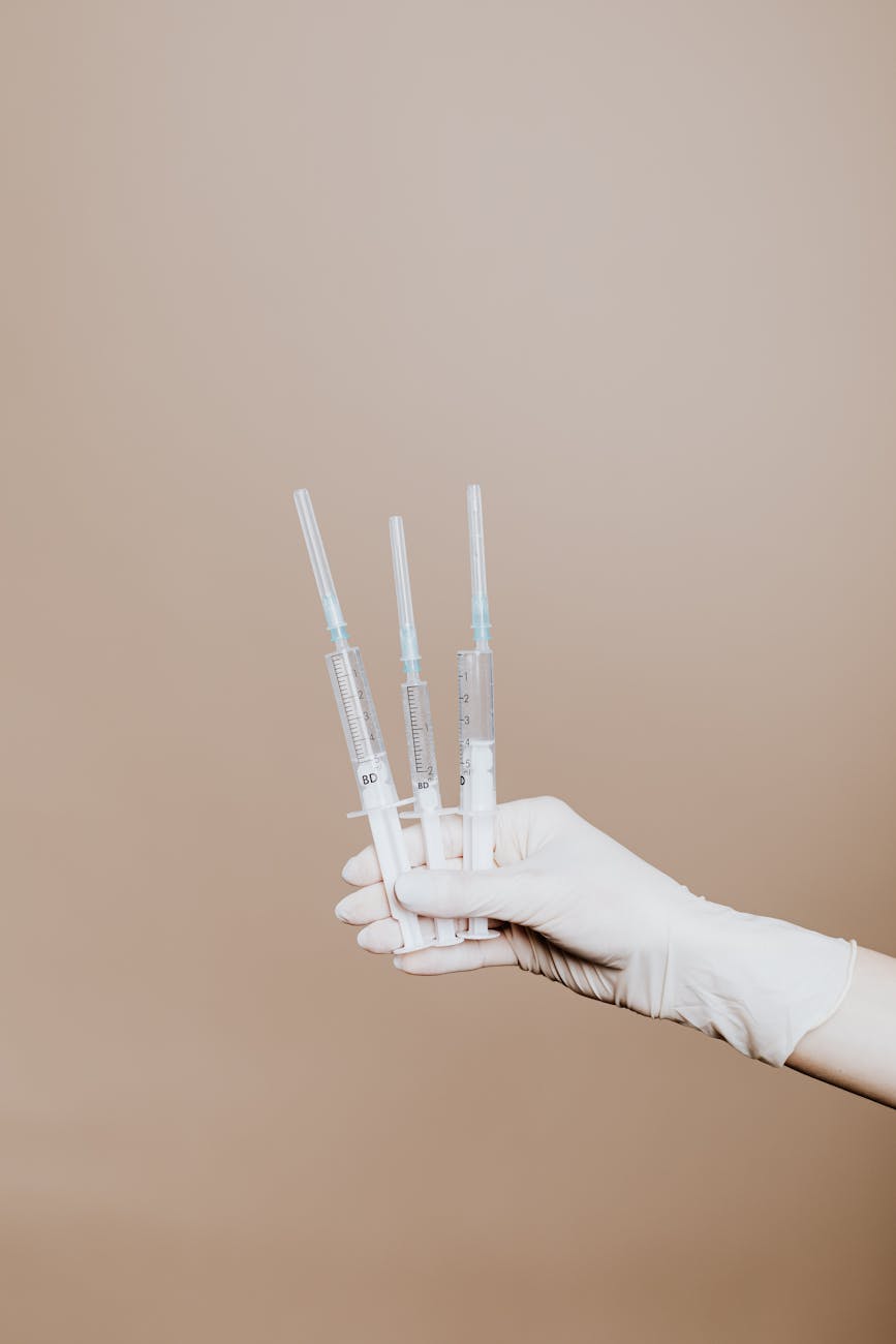 person holding three syringes with medicine