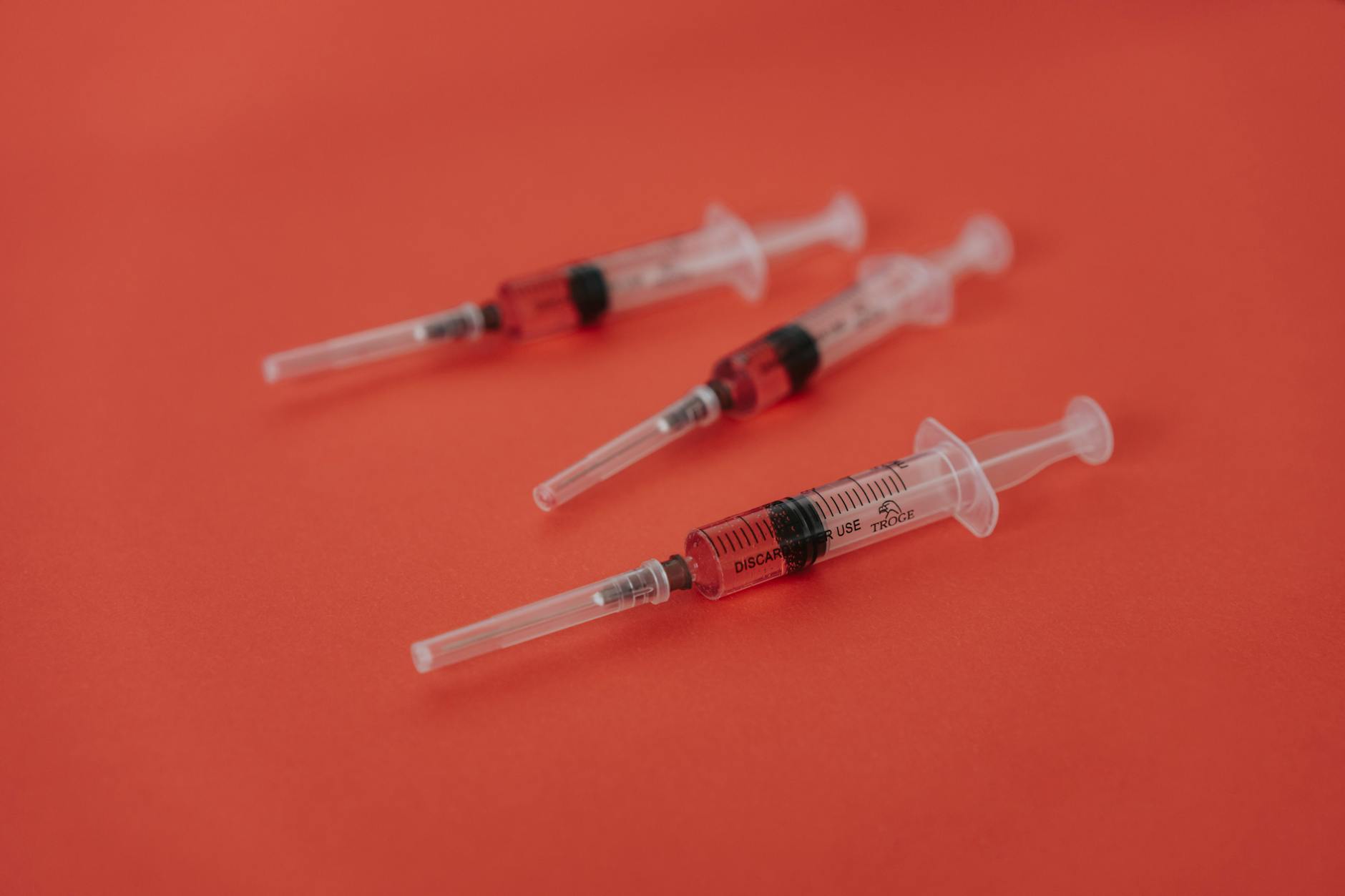 close up shot of syringes on a red surface